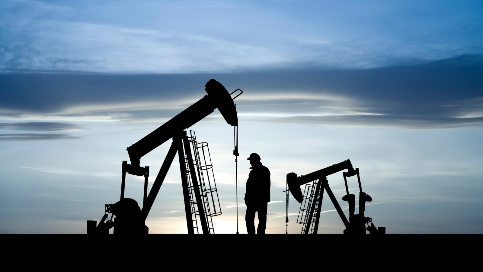 Oil pumpjacks silhouetted at dusk, the upstream supply that the IEA and OPEC forecast so differently.
