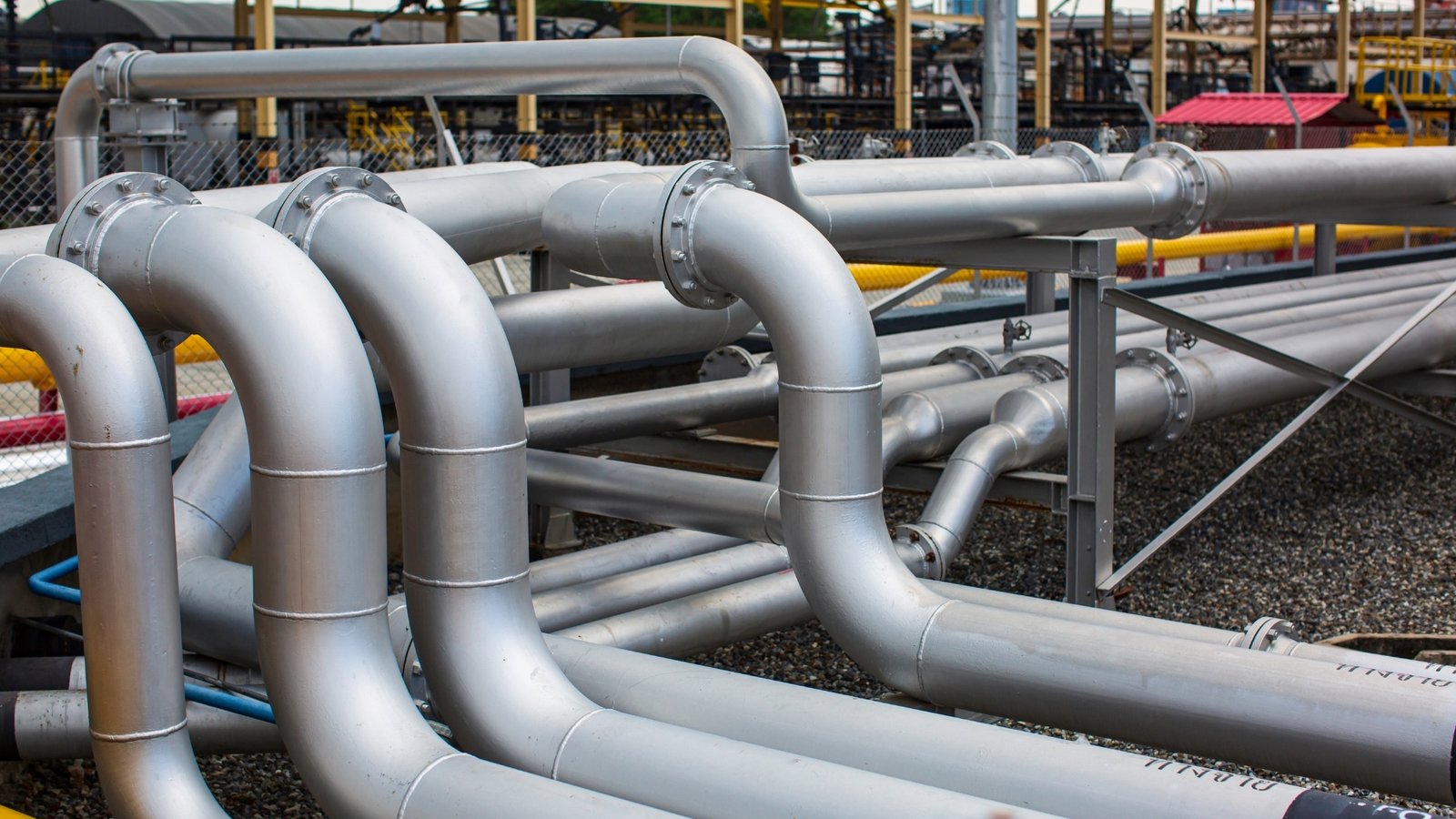 Interwoven pipe runs at an energy processing facility, the routed, engineered flows a long-cycle nurture system mirrors.