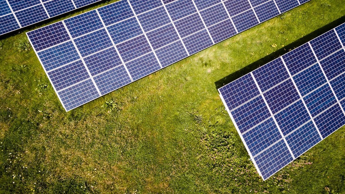 Overhead view of two ground mounted solar panel arrays standing on green grass